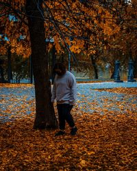 Full length rear view of man standing by tree during autumn