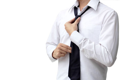 Midsection of businessman wearing necktie while standing against white background