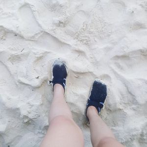 Low section of woman standing on sand