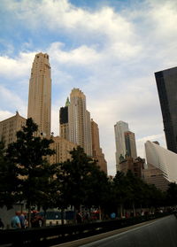 Low angle view of skyscrapers against cloudy sky