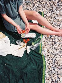 Low section of woman preparing food while sitting at beach