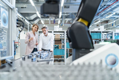 Businessman and businesswoman talking in a modern factory hall