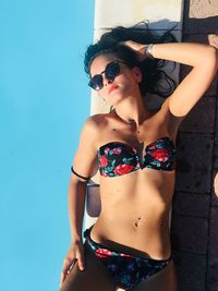 Young woman in sunglasses lying at poolside