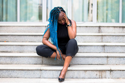 Full length of woman with blue hair sitting on steps