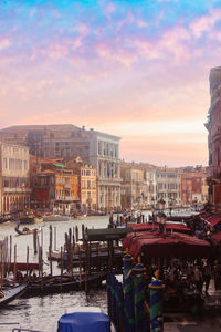 Boats moored in canal against buildings during sunset