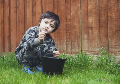 Boy picking flowers on grassy land in yard