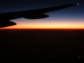 Close-up of airplane wing against sky during sunset