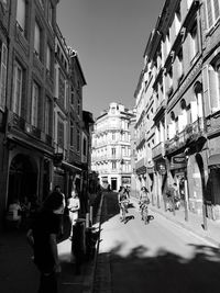 People walking on street in city against clear sky