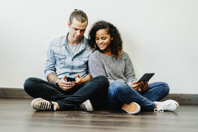 Couple using technologies while sitting on floor at home