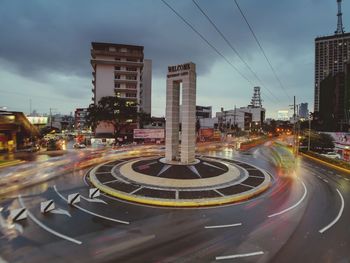 Vehicles on road against sky in city