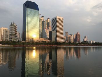 Reflection of buildings in lake against sky in city