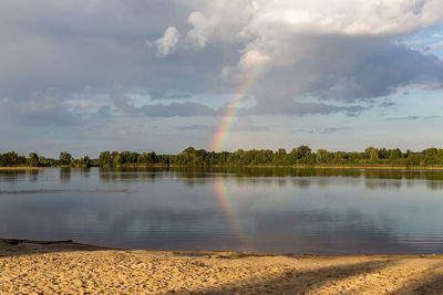 Scenic view of rainbow over lake against sky