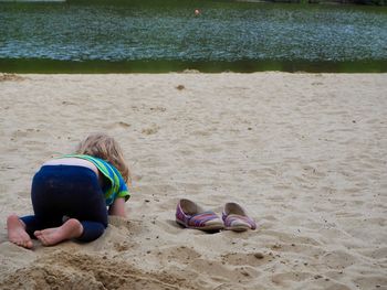 Playful girl by shoes at beach