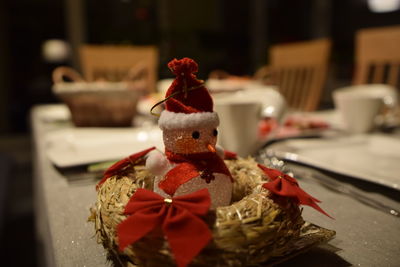 Close-up of snowman figurine in artificial nest on table during christmas