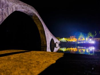 Bridge over illuminated buildings against clear sky at night