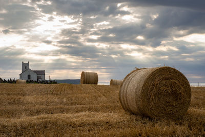 Hay bales on field against sky