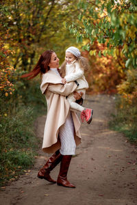 Mother and daughter walking on dirt road in forest