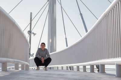 Full length of woman sitting on bridge
