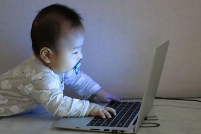 Cute baby boy using laptop at home