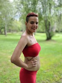 Side view portrait of pregnant woman smiling while standing at park