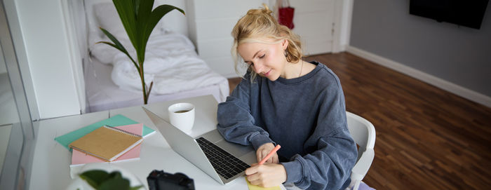 Side view of young woman using digital tablet at home