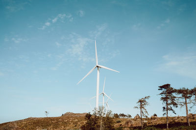 Low angle view of windmills on landscape against sky