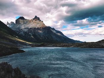 Scenic view of lake and mountains against dramatic sky