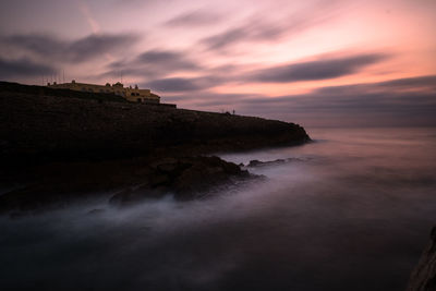 Rock formation on sea against sky during sunset