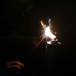 Hand holding lit candle in the dark