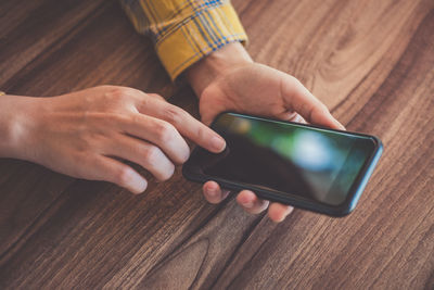 Midsection of man using mobile phone on table