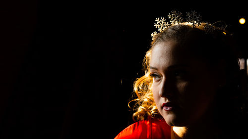 Side view of woman looking away against black background