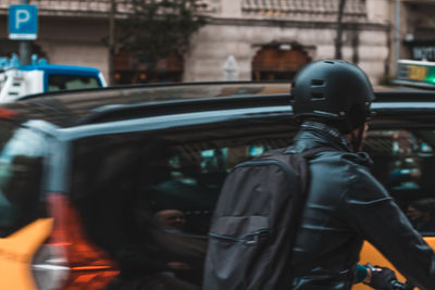 Rear view of man driving car in city