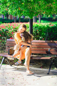 Portrait of woman sitting on bench at park