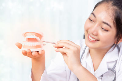 Close-up of smiling doctor holding dental implant in clinic