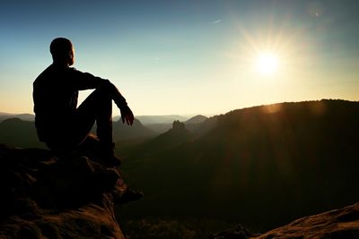 Silhouette man against mountains against sky during sunset