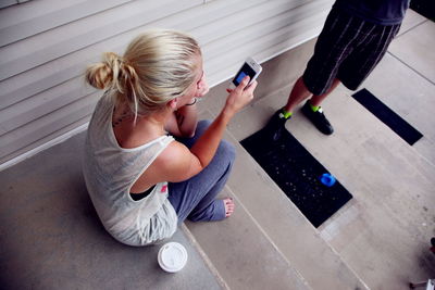 High angle view of woman using phone on steps by man