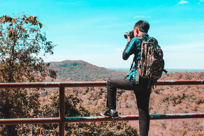 Man photographing with umbrella standing on railing