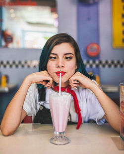 Portrait of woman drinking smoothie in cafe