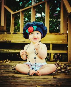 Cute smiling girl with necklace wearing hat at porch