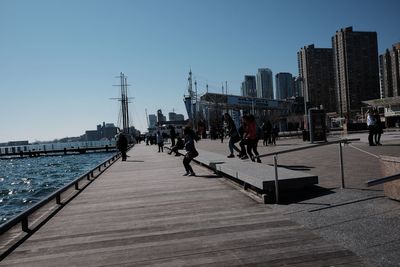 People on city buildings against clear sky