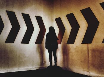 Rear view of woman standing against wall