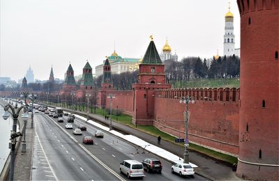 Vehicles on road amidst buildings against sky in city