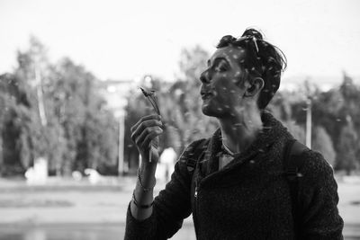 Man blowing dandelions against trees