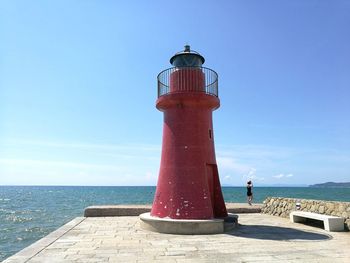 Lighthouse by sea against sky