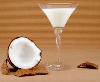 Halved coconut with glass of coconut milk