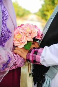 Midsection of wedding couple holding bouquet