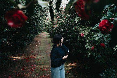 Young woman looking away while standing amidst plants