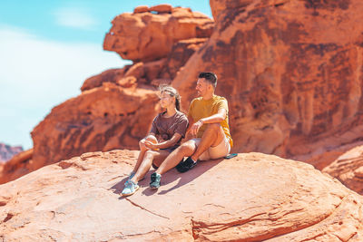 Rear view of woman sitting on rock