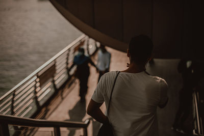 Rear view of men standing by railing against sea