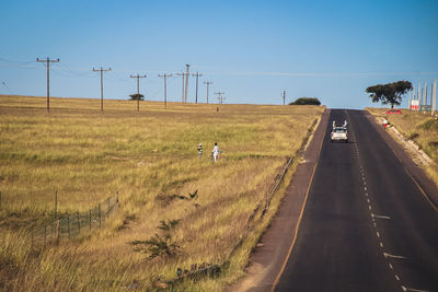 Man riding motorcycle on road amidst field against clear sky